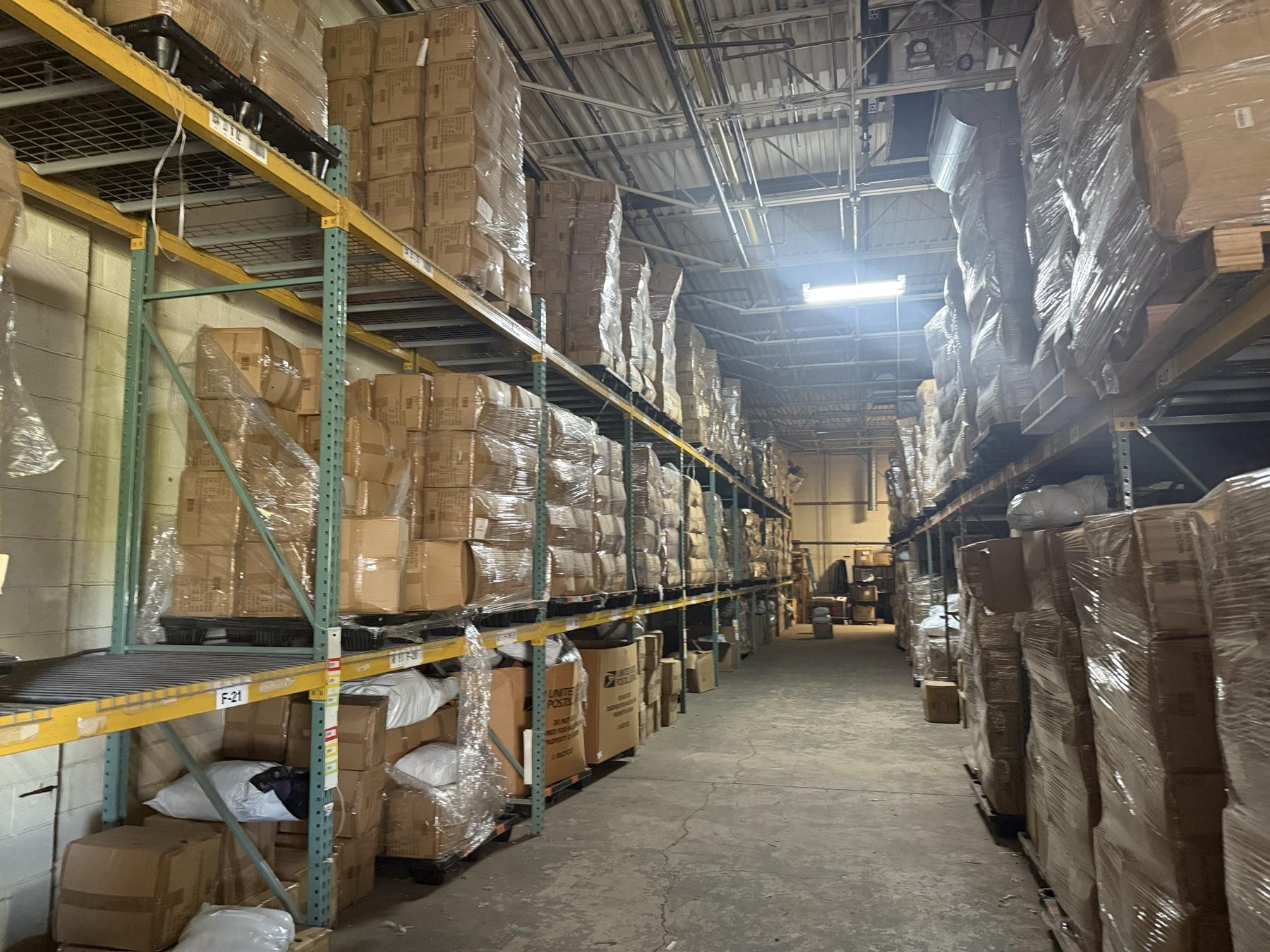 Lit warehouse aisle with stocked pallet racking on both sides