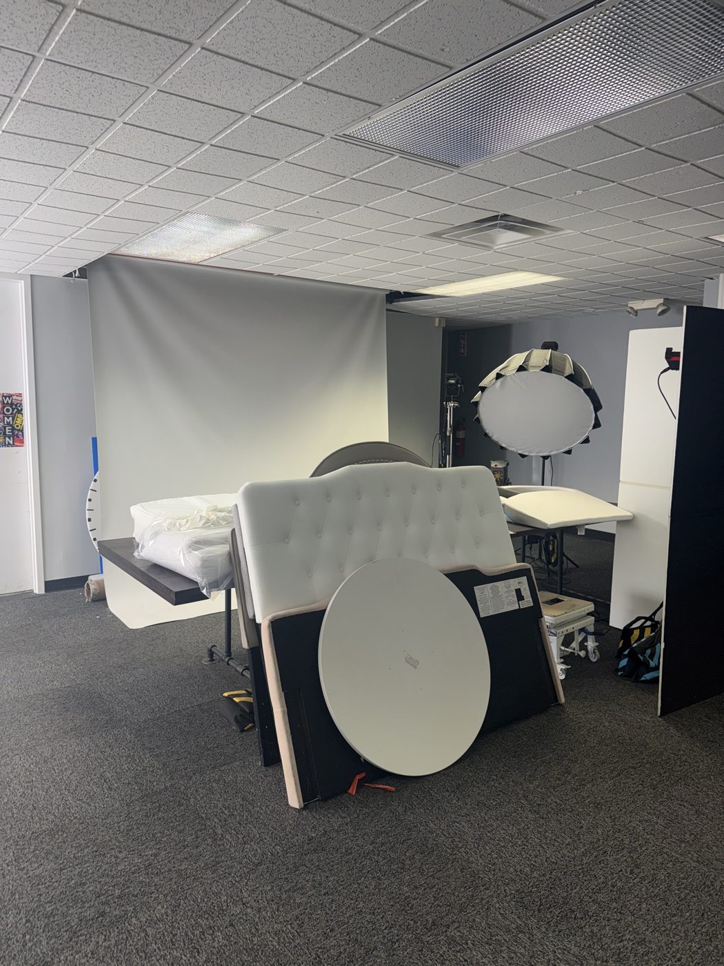 Bed set with an upholstered headboard, white backdrop and a beauty dish for lifestyle shots
