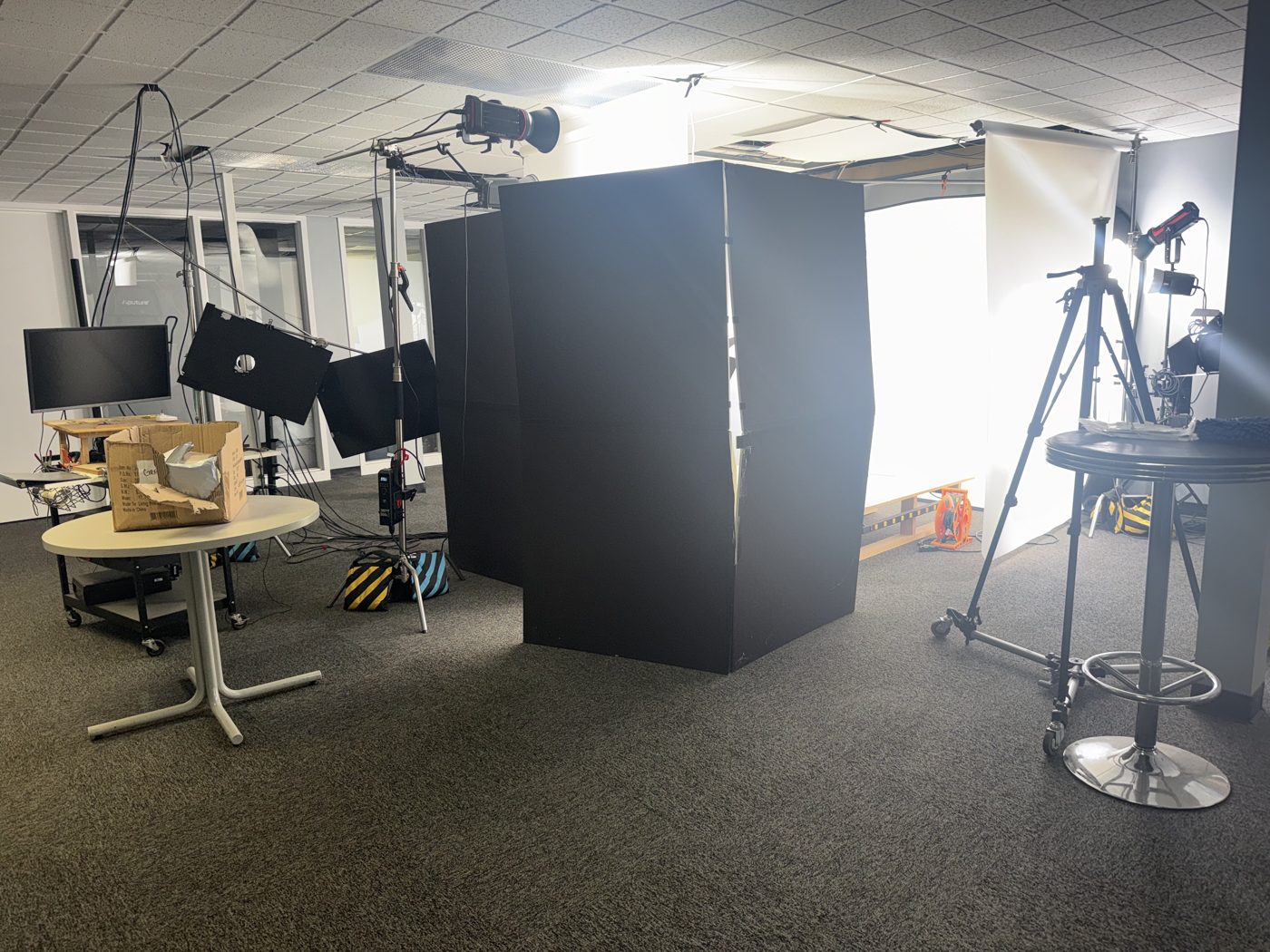 Blacked-out shooting tent beside a lit cyclorama with strobes on stands